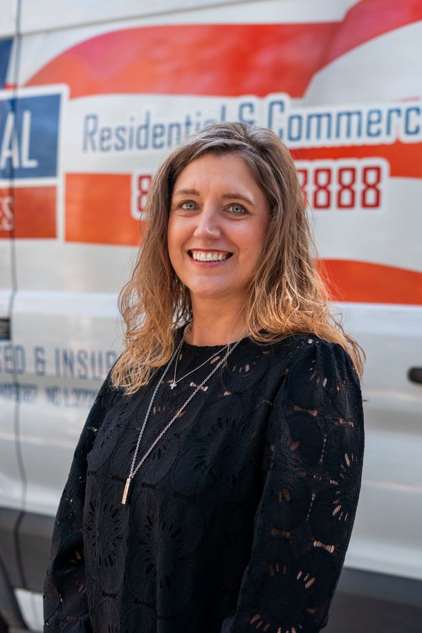 Woman smiling, standing in front of a white van with red and blue lettering that says