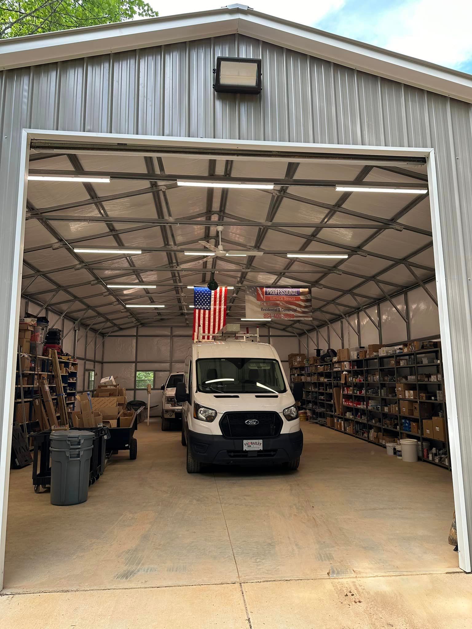 Warehouse interior with a van parked inside, shelves of goods on either side, American flag hanging.