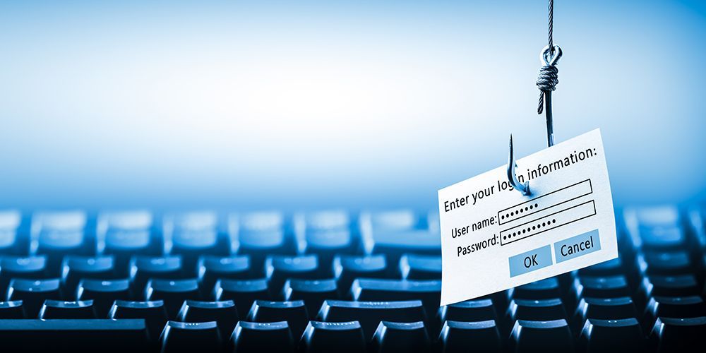 A fishing hook dangling over a computer keyboard, holding a login prompt as bait to represent a phishing attack.