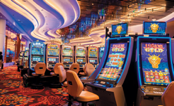 A casino with a lot of slot machines and chairs.