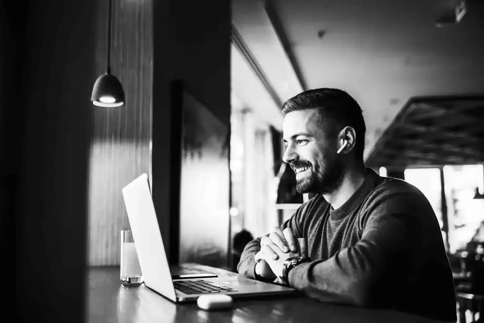 A man is sitting at a table using a laptop computer.