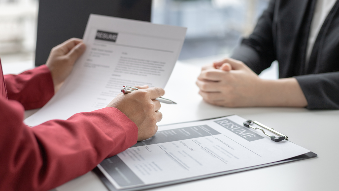 A woman is holding a resume during a job interview.
