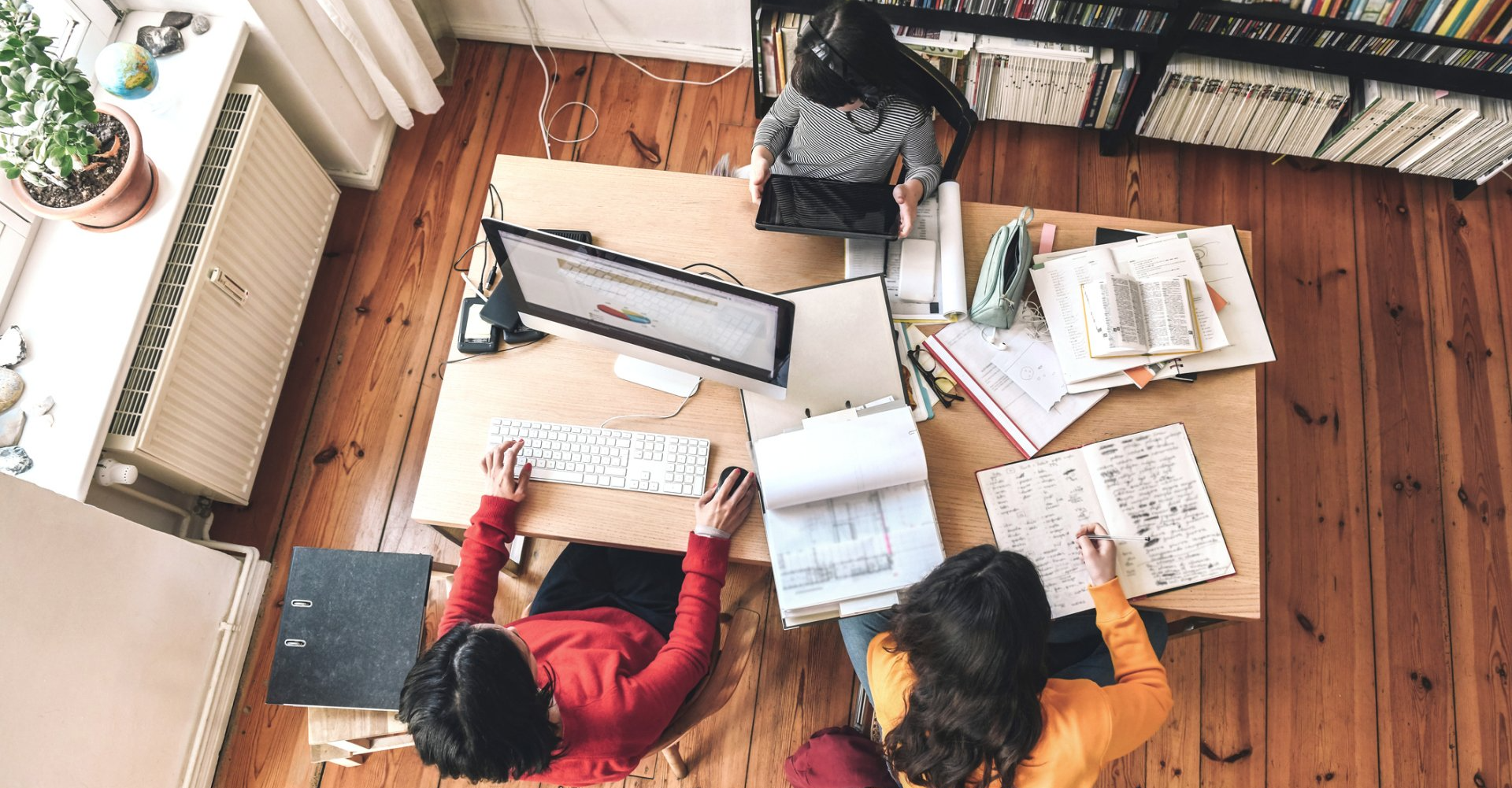 A group of people are sitting at a table working on computers.