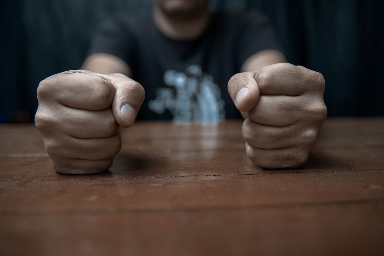 A man is sitting at a table with his fist in the air.