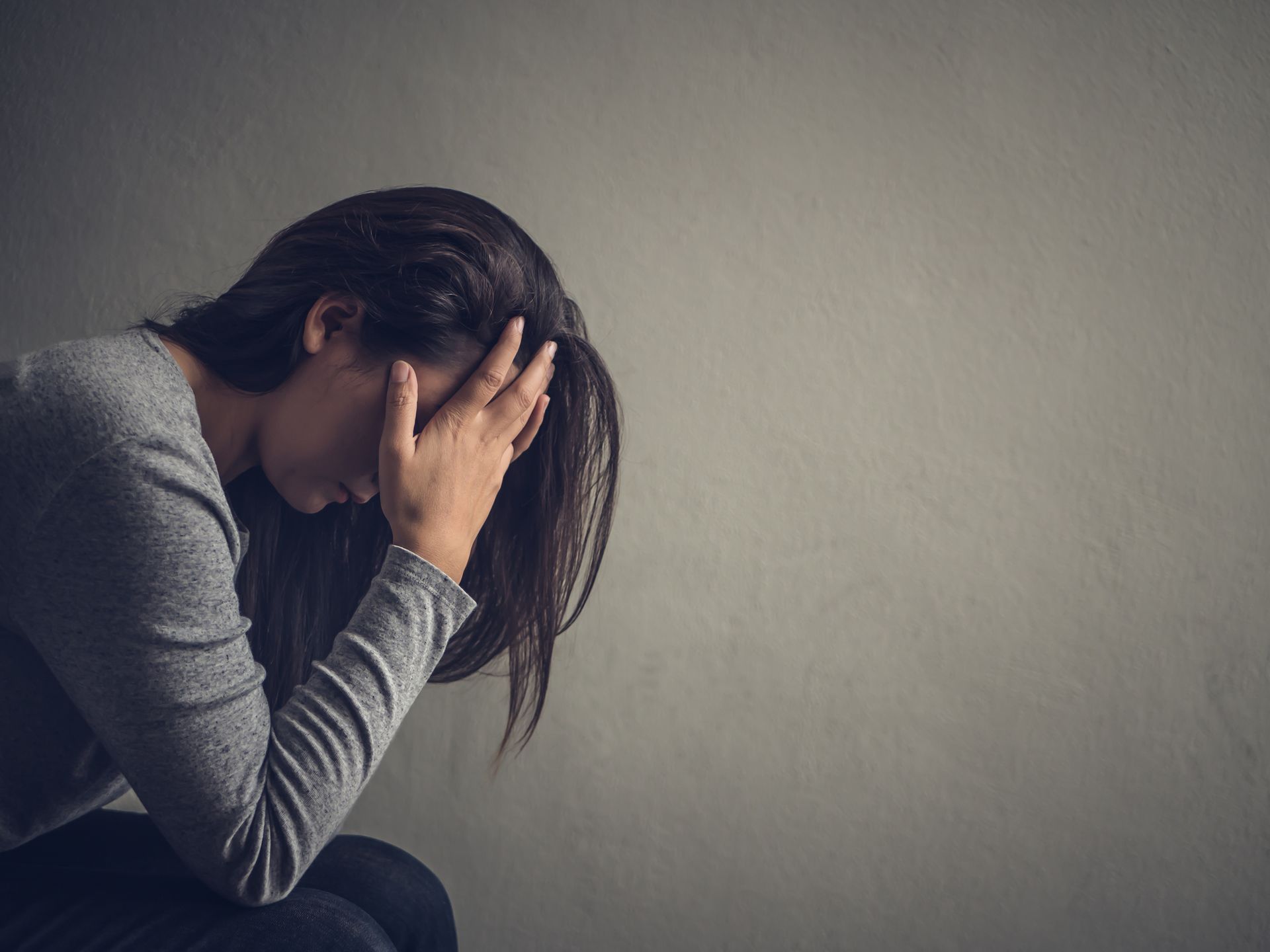 A woman is sitting down with her head in her hands.