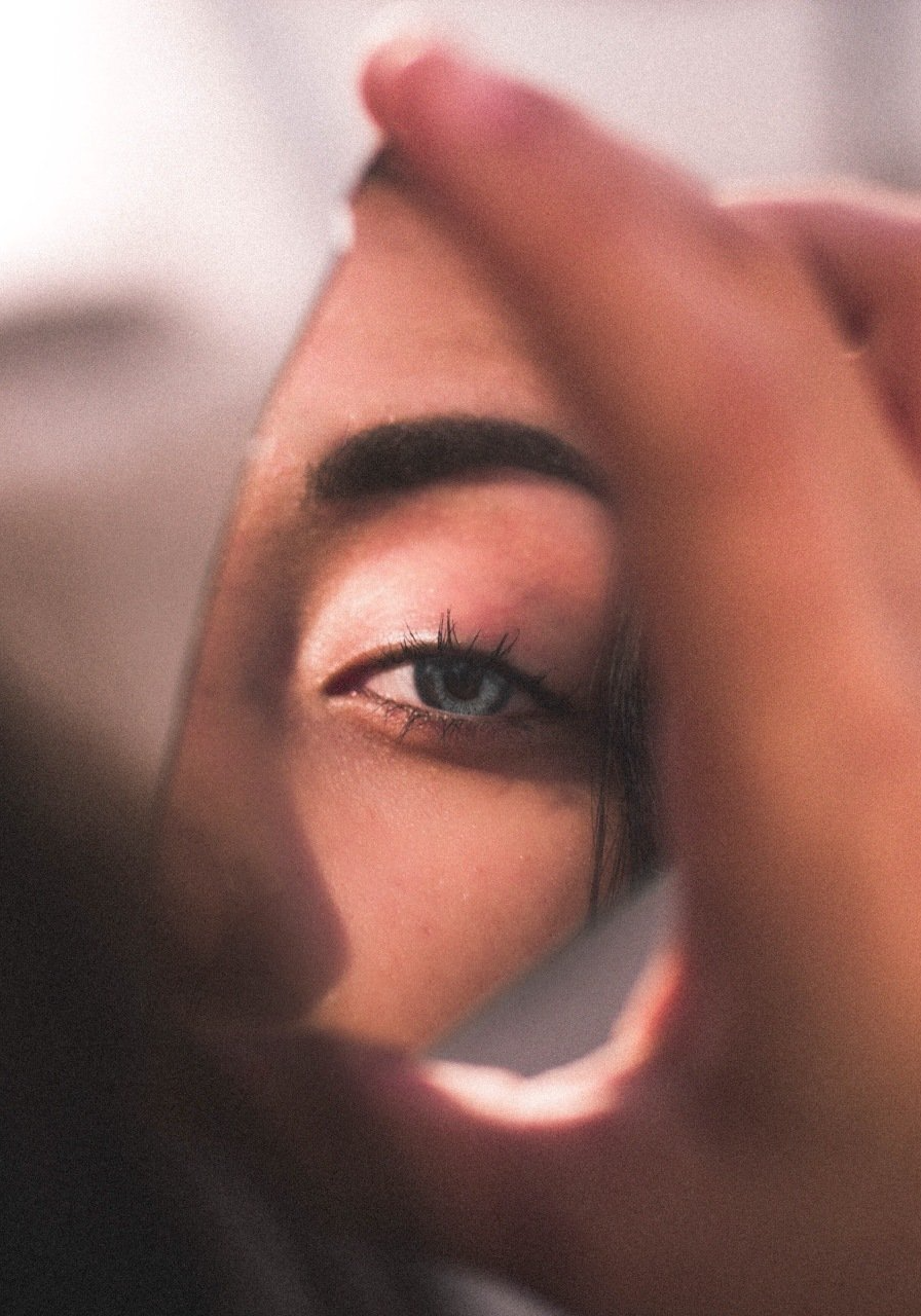 A woman is looking at herself in a mirror.