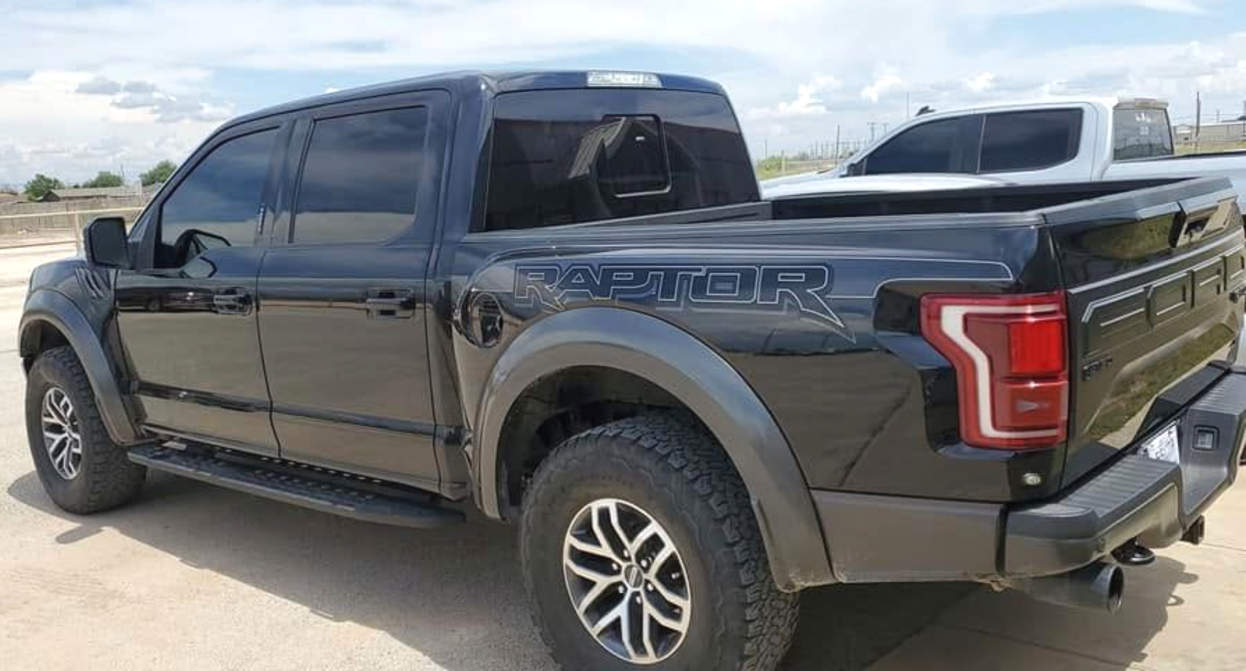 Black pickup truck parked outdoors on a sunny day, side and rear view visible