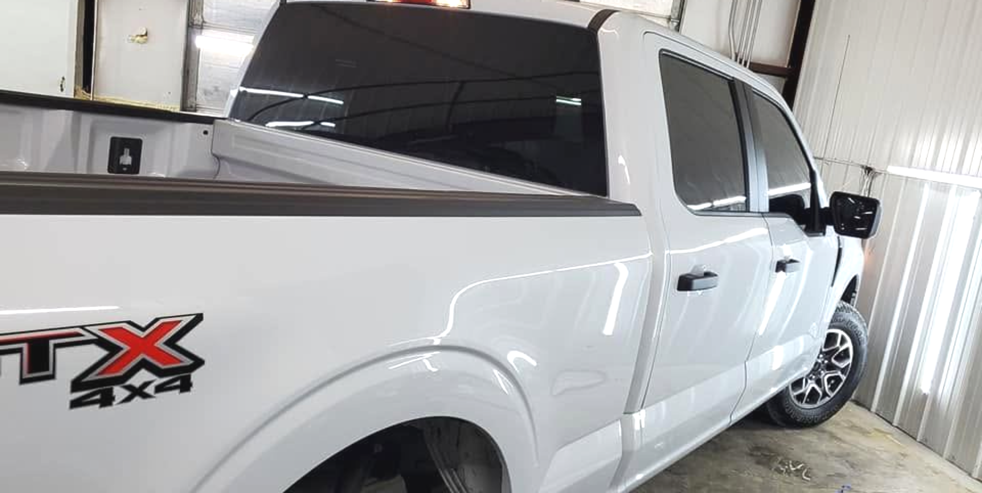 White pickup truck with tinted windows parked indoors, side view showing the rear bed and TX 4x4 decal