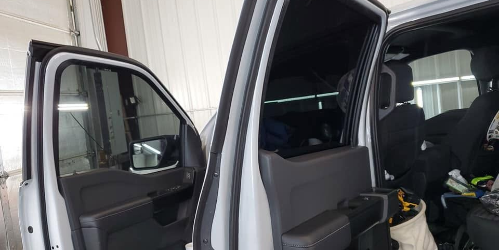 Open van interior with sliding side door open, showing seats and equipment inside garage-like setting
