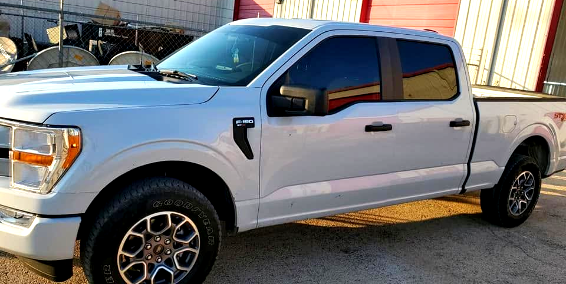 White extended cab pickup truck parked outdoors beside a building at sunset