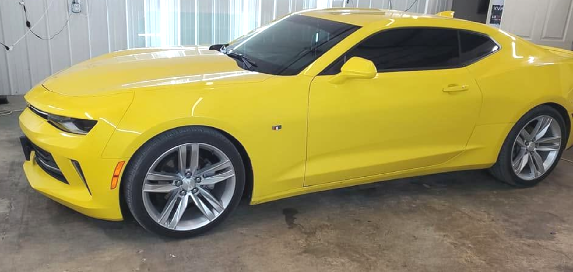 Yellow sports car parked indoors on a concrete floor, side view
