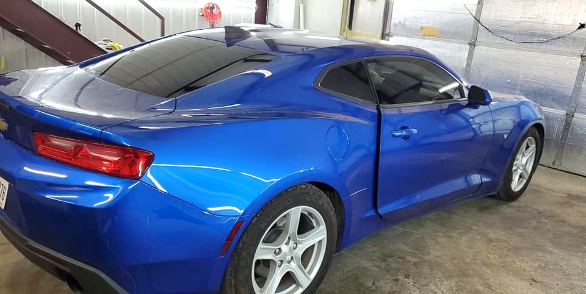 Blue sports coupe parked in a garage, rear three-quarter view
