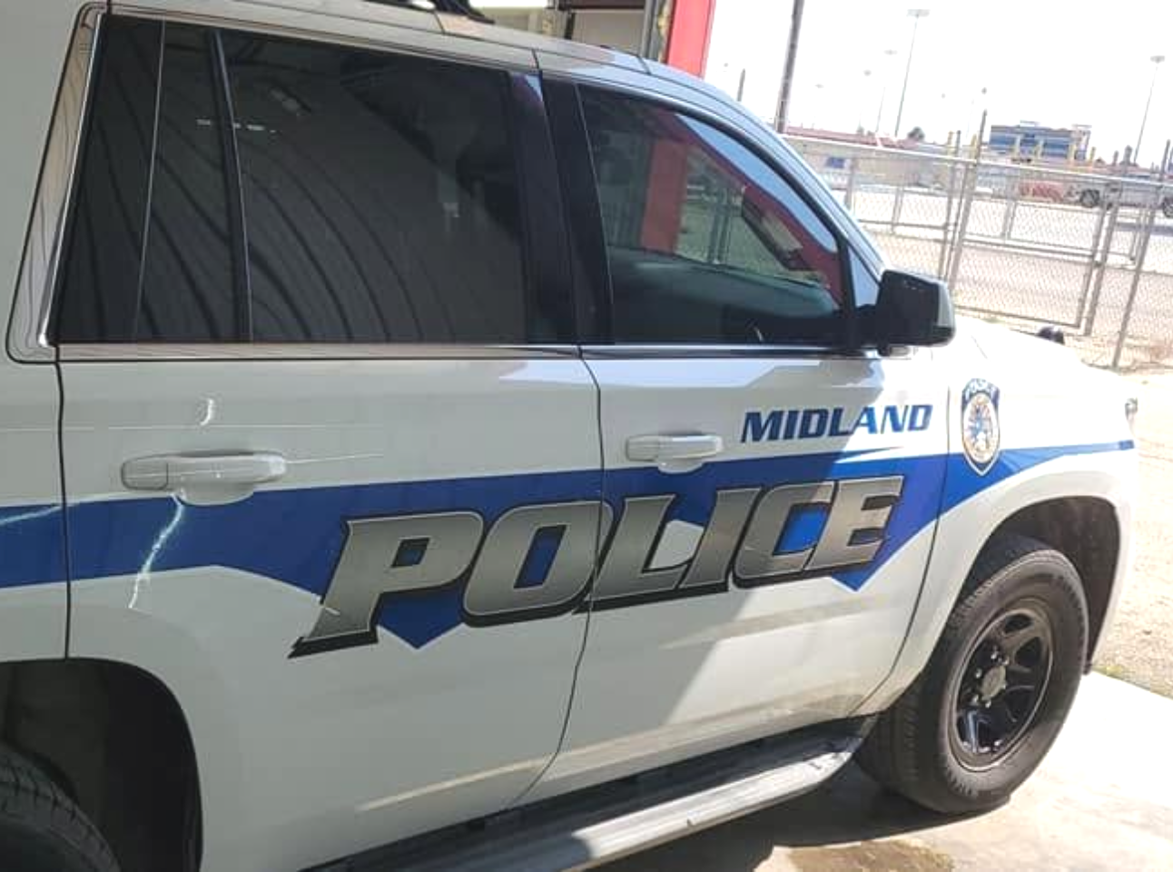 Midland police SUV with blue stripe parked outdoors, side view
