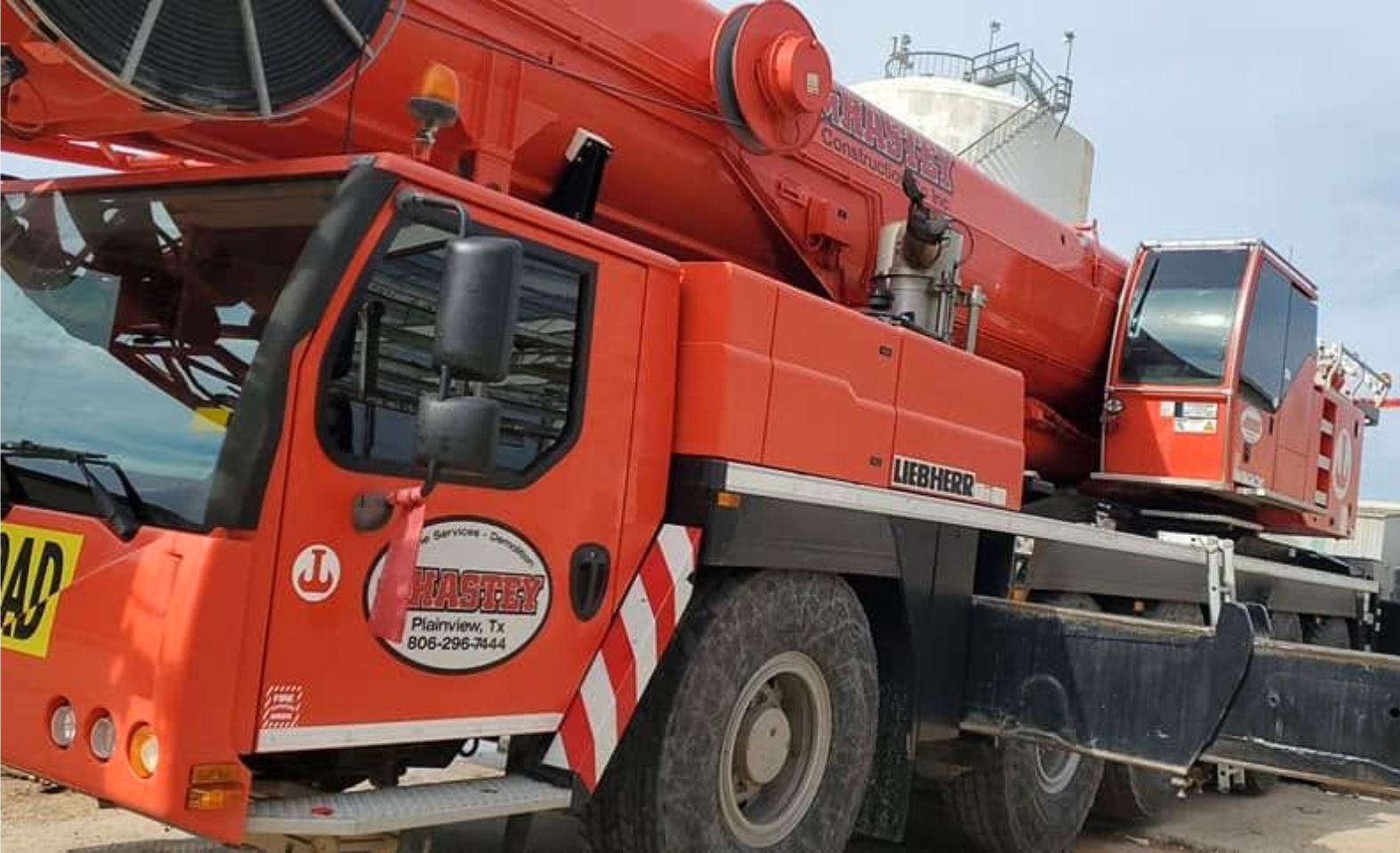Red crane truck with black-and-white striped safety markings parked on a street.