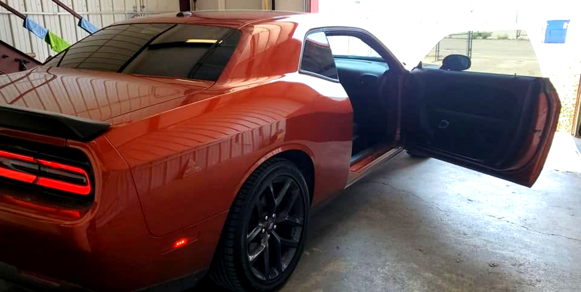 Orange sports car parked in a garage with the driver door open