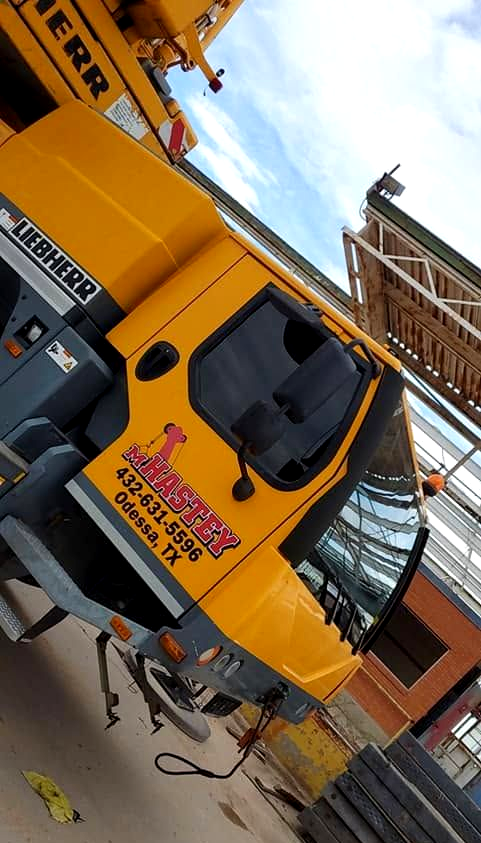 Yellow construction truck with red logo parked beside scaffolding at a building site