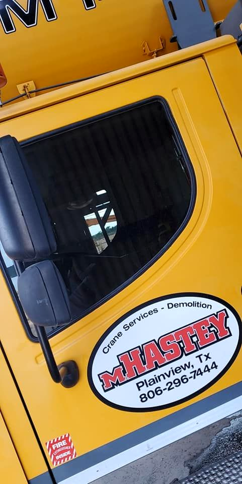 Yellow truck door with black window and a white oval “MASTEY” logo decal.