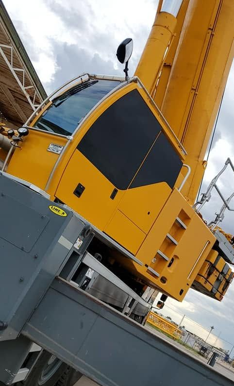 Yellow industrial crane structure with a large gray base against a cloudy sky