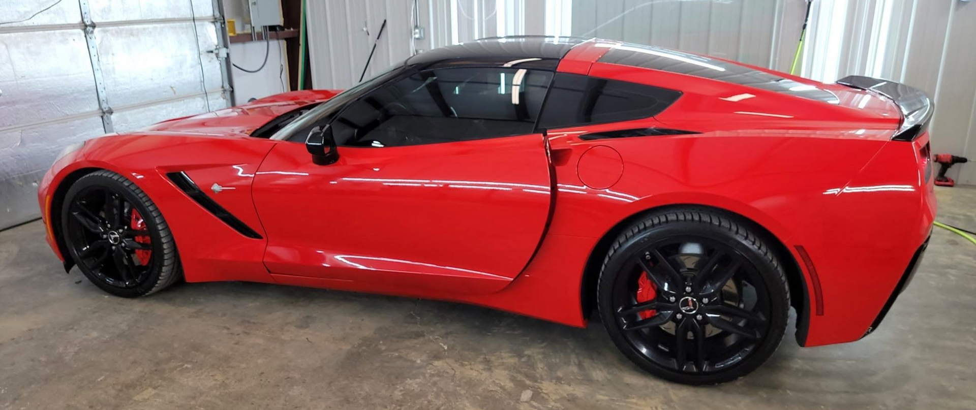 Red sports car with black accents parked indoors in a garage