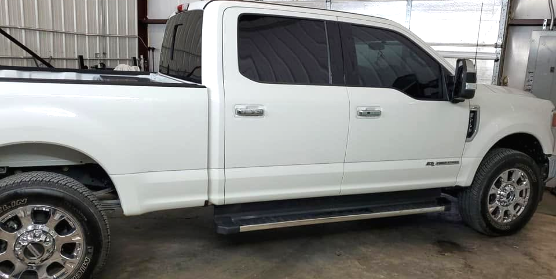 White pickup truck with dark-tinted windows and chrome wheels parked indoors