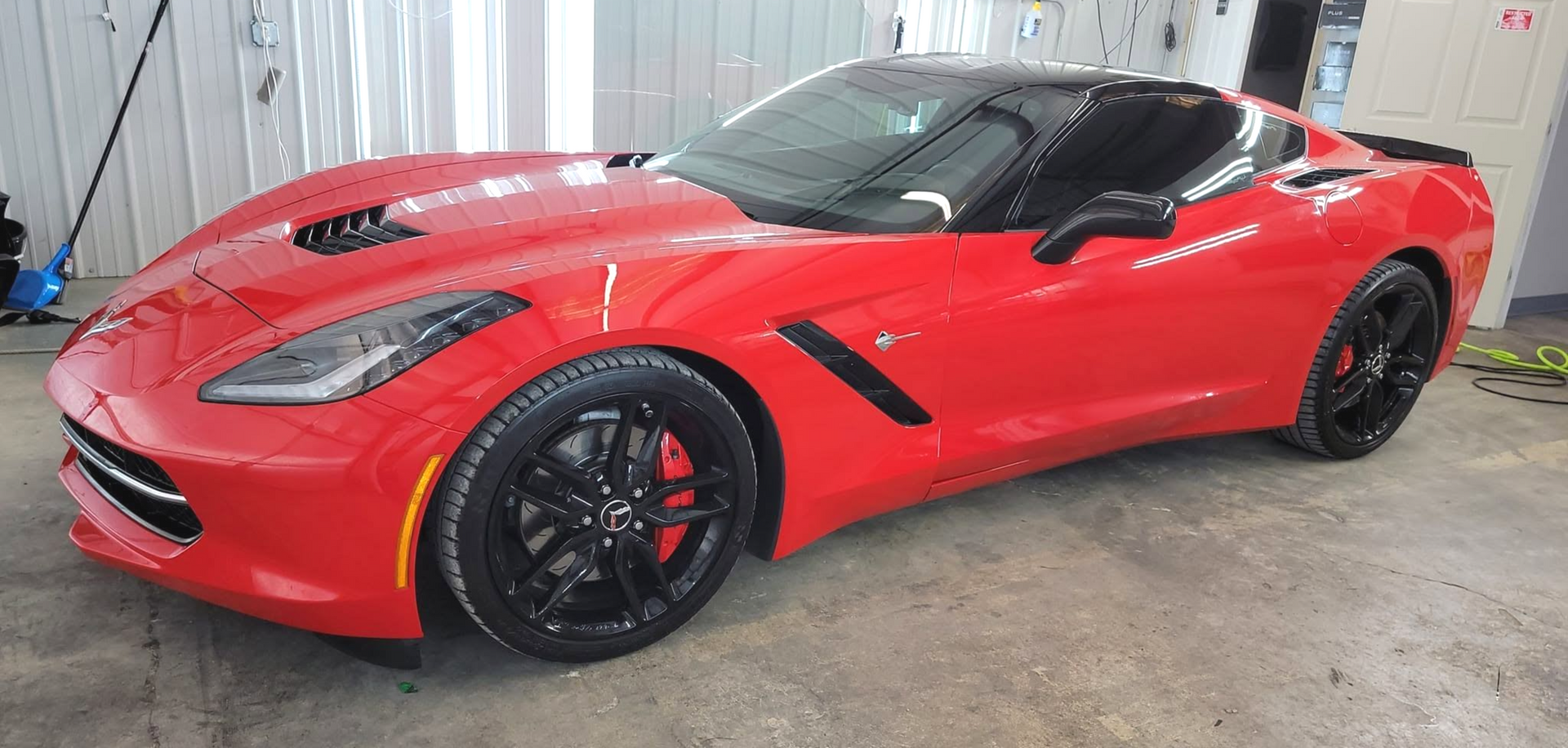 Red sports convertible parked indoors on a concrete floor.