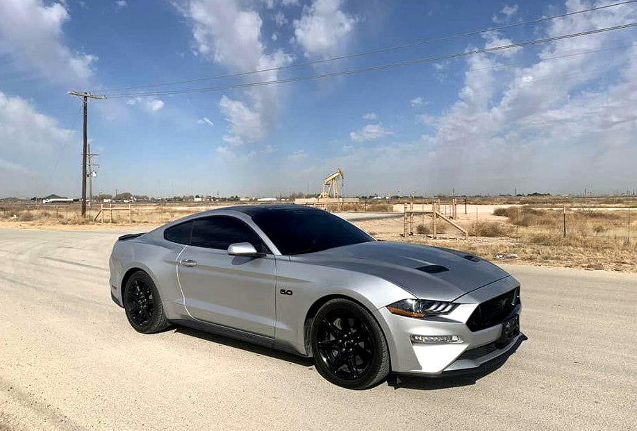 Silver sports car on a desert road under a partly cloudy sky