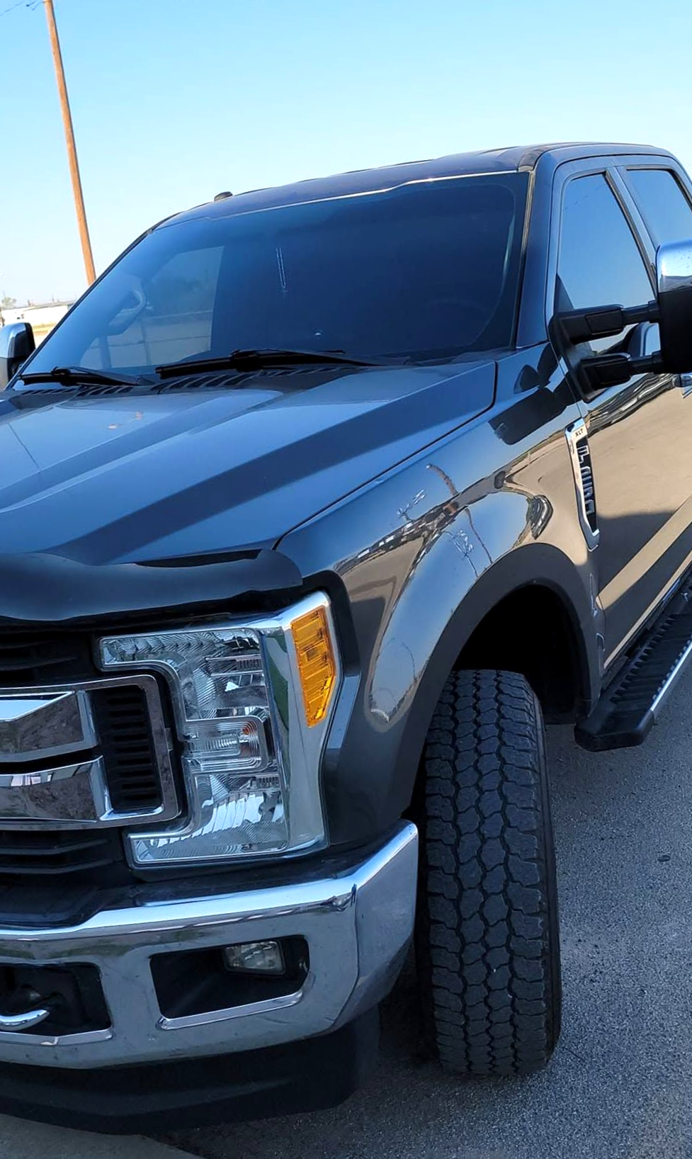 Black pickup truck parked outdoors on a sunny day, front-left view.