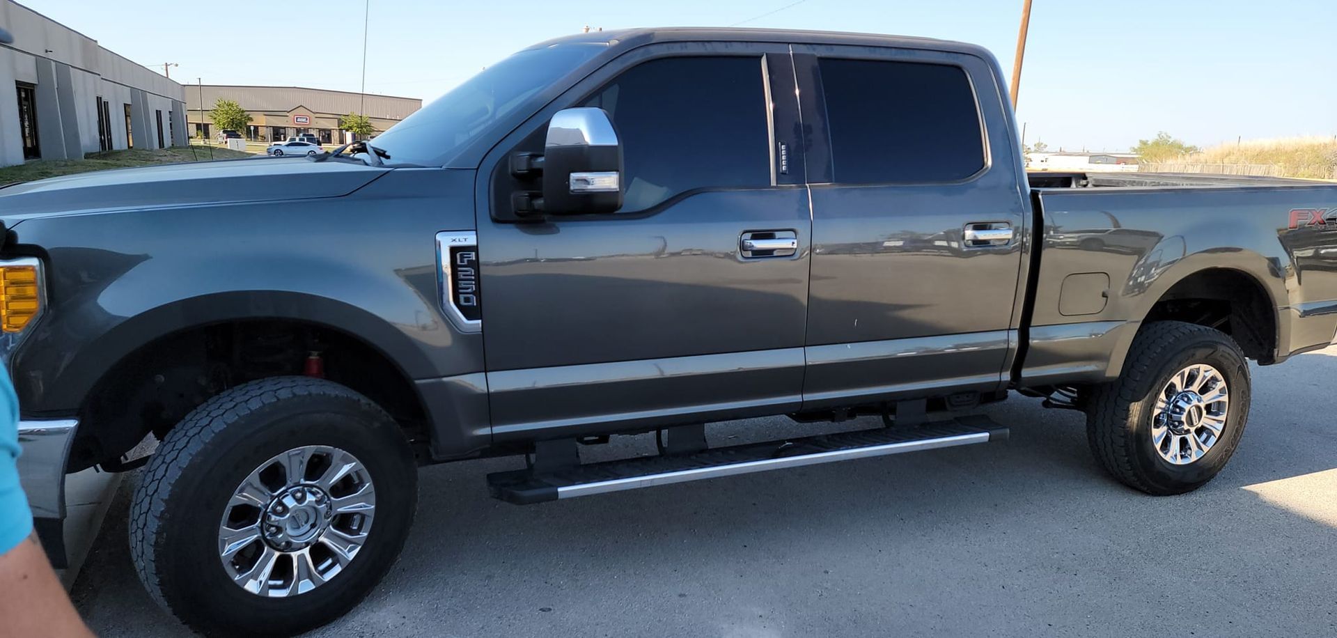 Dark gray pickup truck parked on a sunny street beside a building
