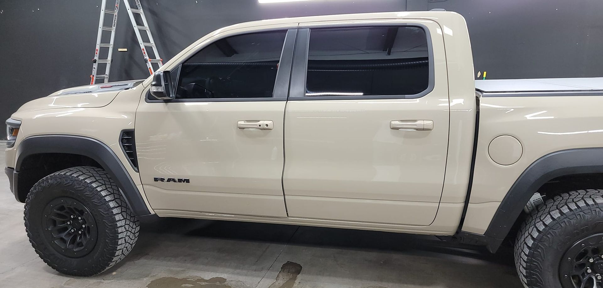 Beige pickup truck in side view with black wheels, parked indoors on a shop floor.