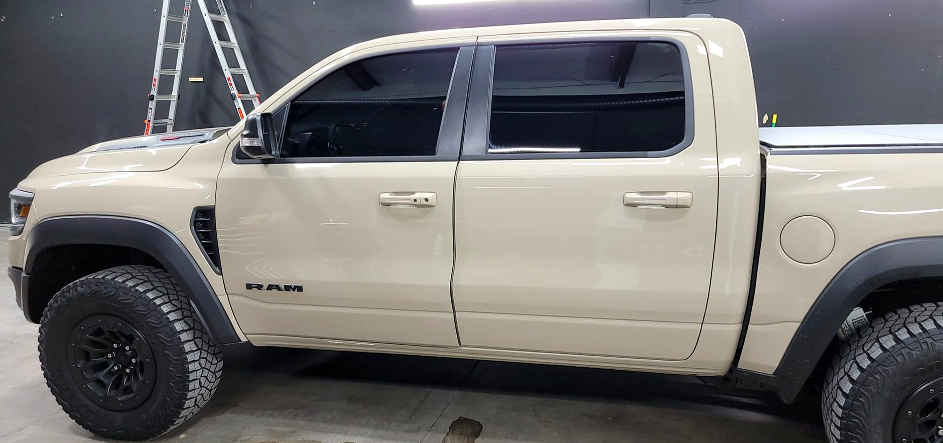 Beige pickup truck parked indoors, side view, with black wheels and tinted windows.