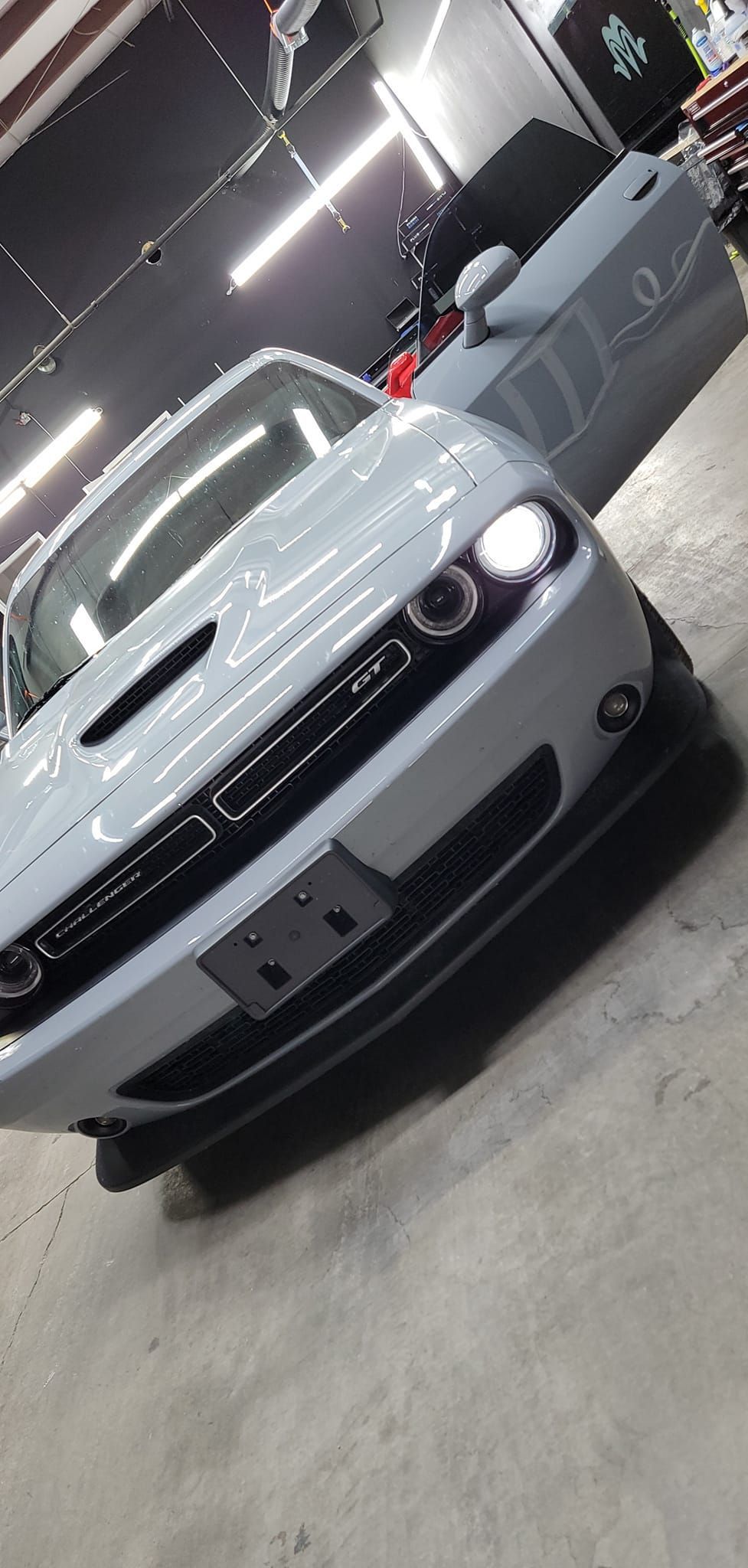 Silver sports coupe parked indoors, angled front view under bright garage lights.