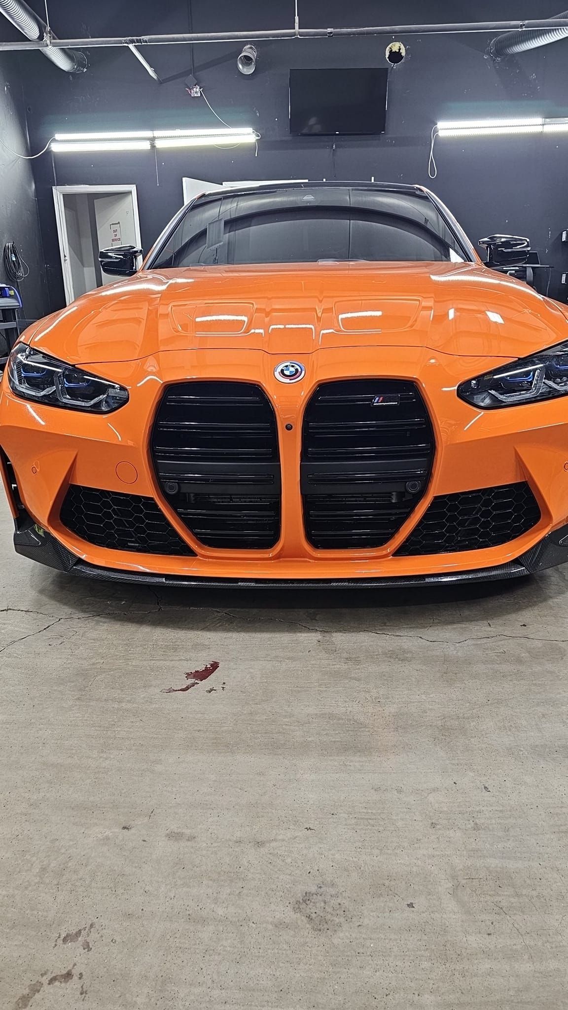 Orange BMW coupe parked indoors in a garage, front view.