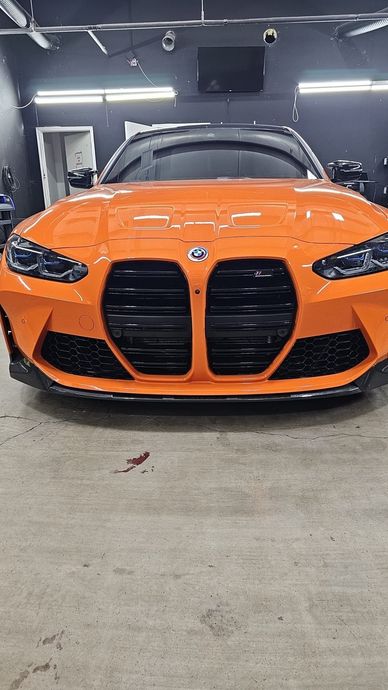 Orange BMW sports car parked in a garage, front view with black grille and headlights.