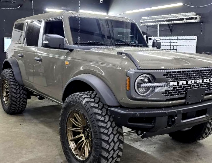 Dark gray lifted pickup truck parked outdoors on a sunny street