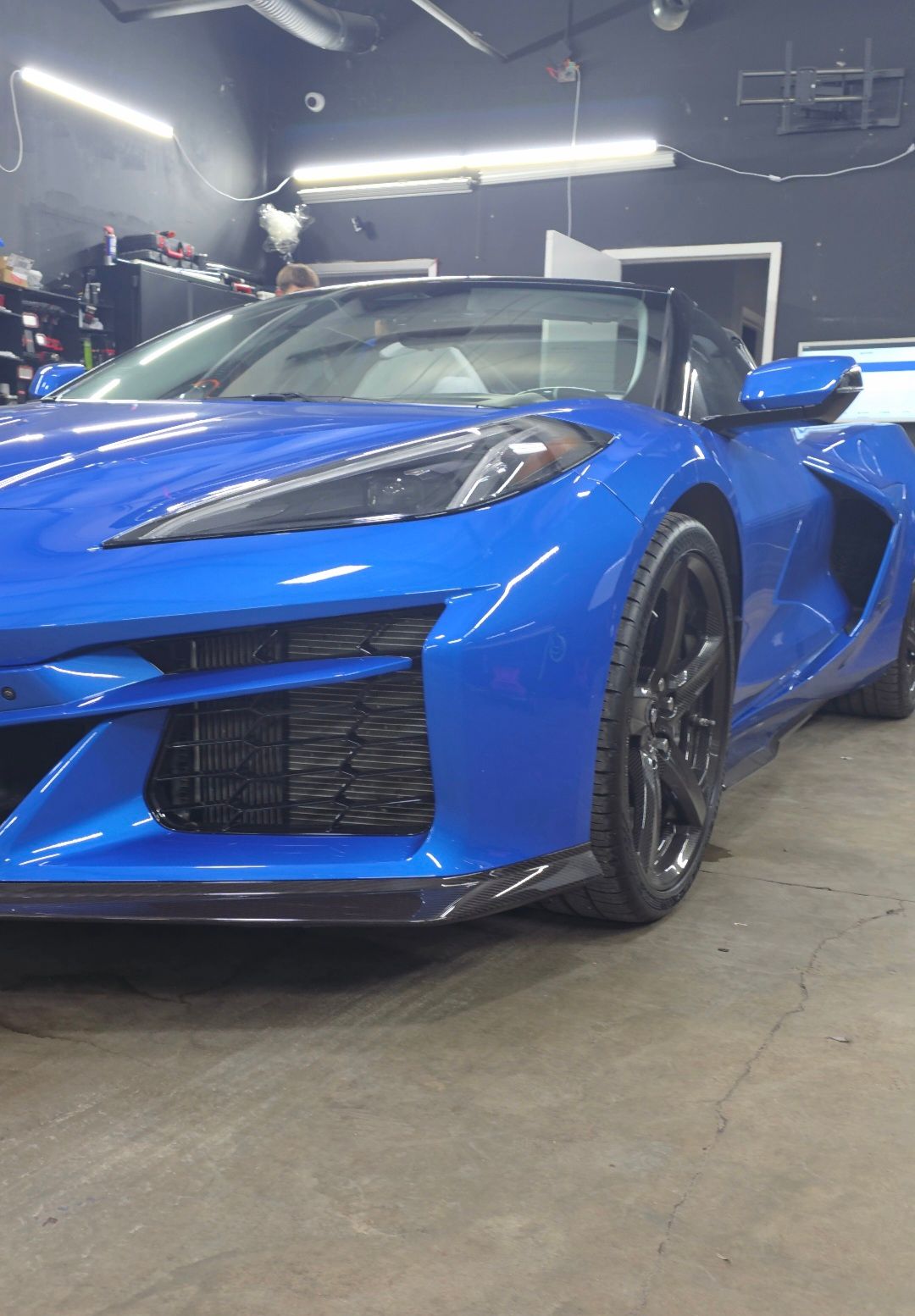 Blue sports car parked in a garage, viewed from the front-left angle.