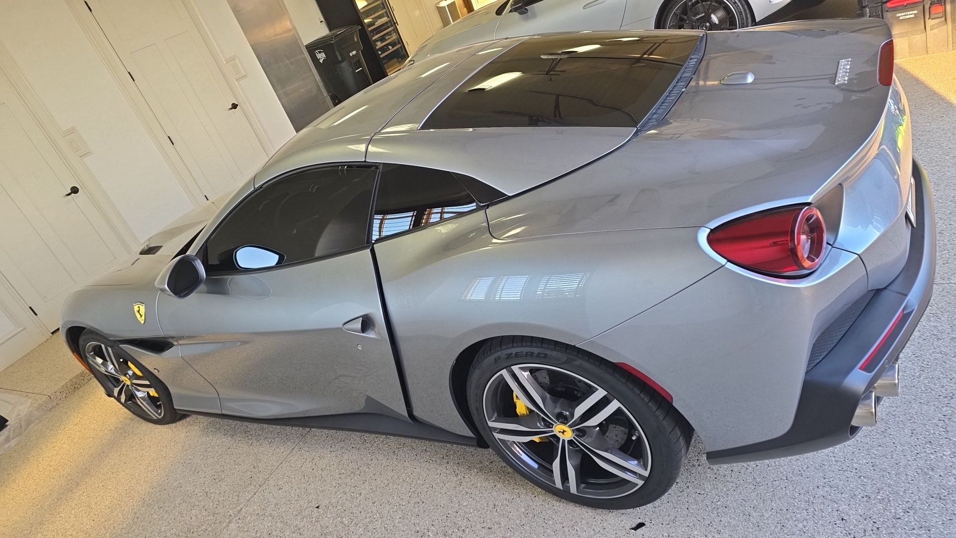 Silver sports coupe parked in a garage, rear three-quarter view with black wheels and red taillights