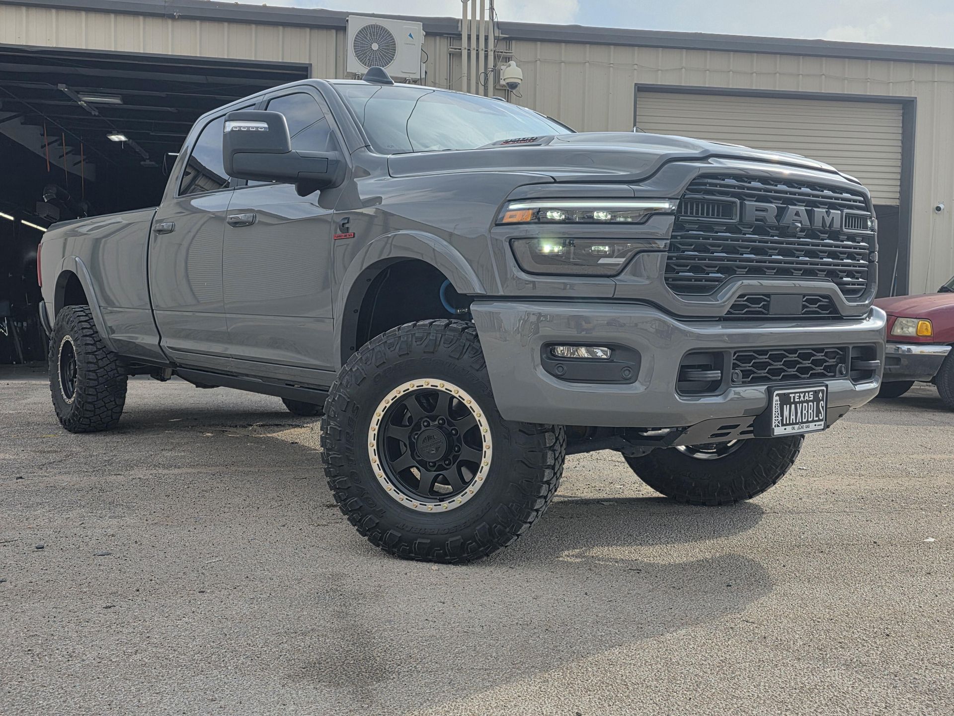 Gray lifted pickup truck parked in front of a garage