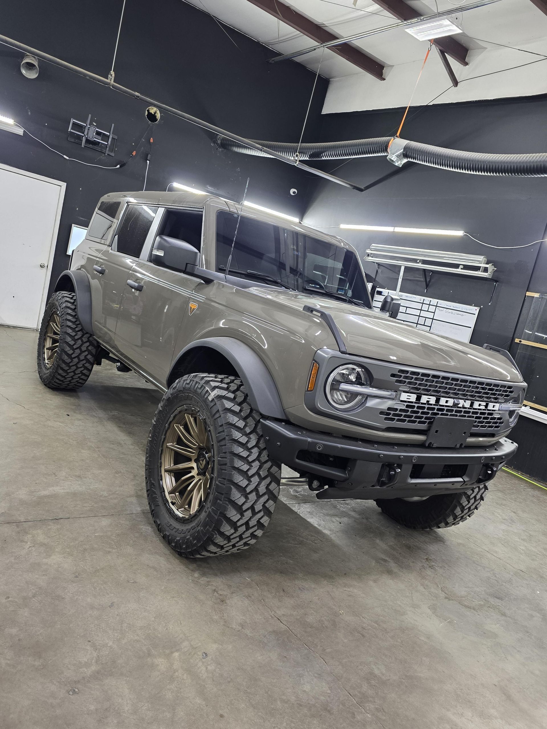 Gray off-road pickup truck with lifted suspension and large tires in a showroom-like garage.