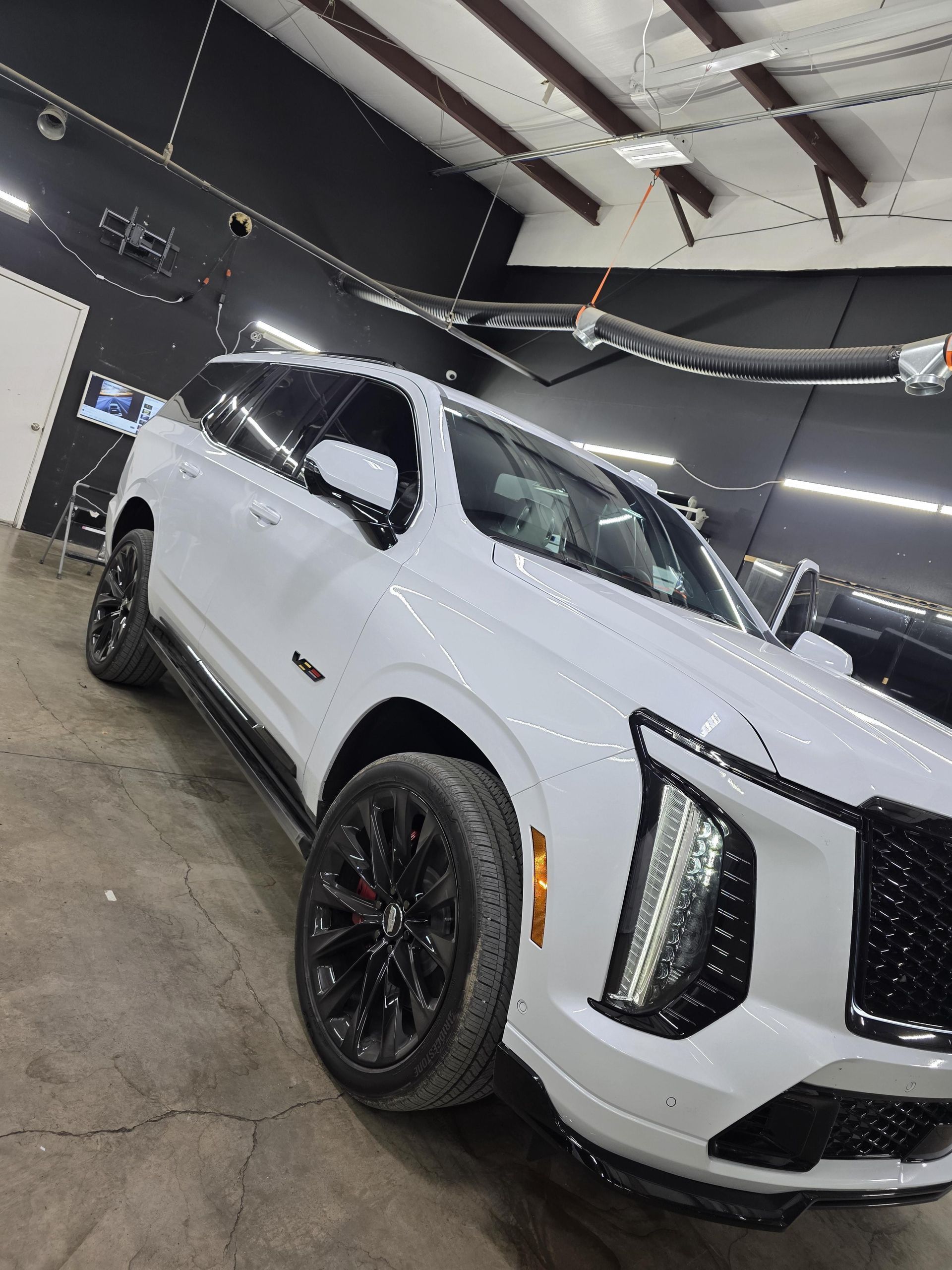 White SUV with black trim parked indoors in a garage, viewed at a slight angle