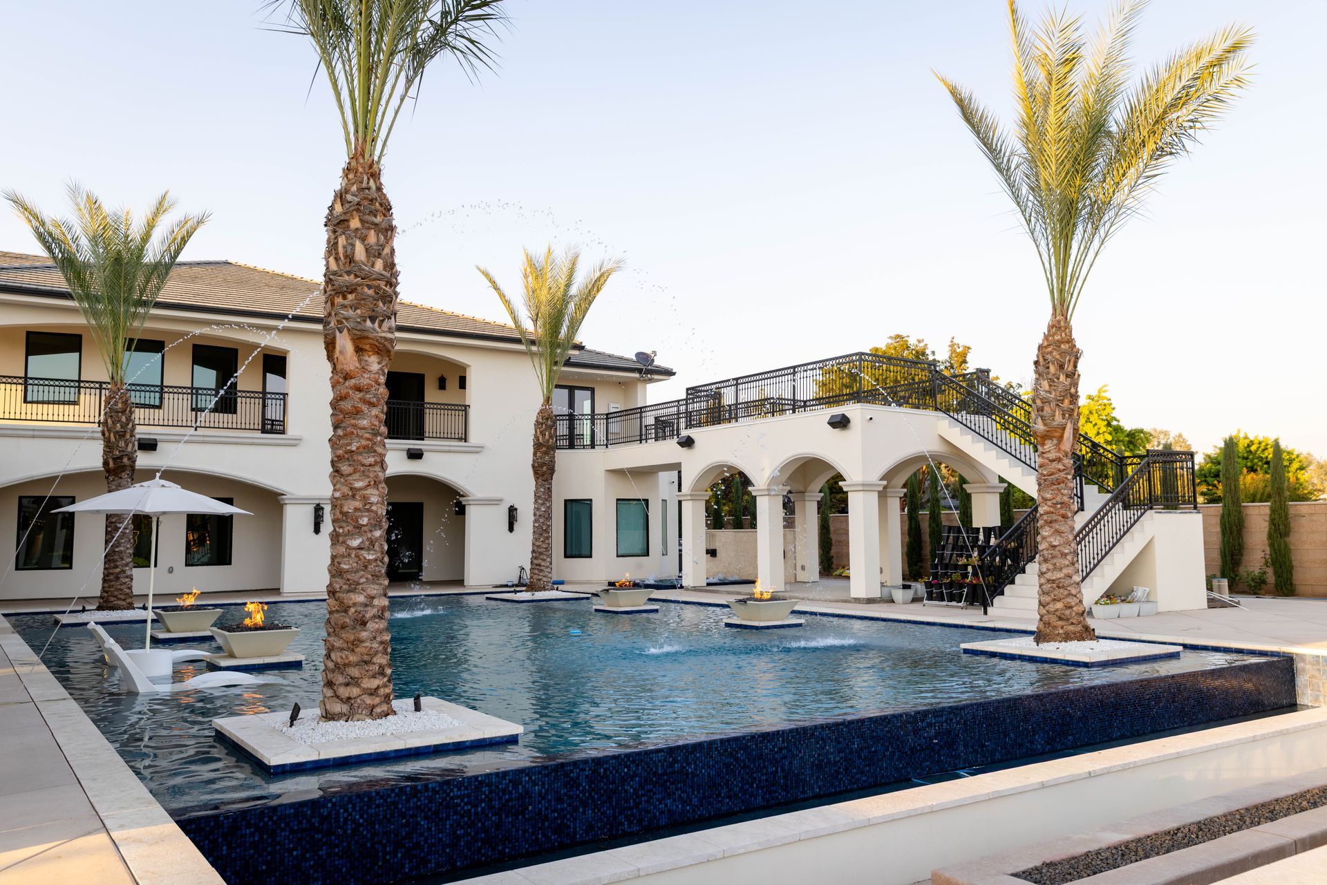 Luxury villa with a large blue pool and palm trees in a sunny courtyard