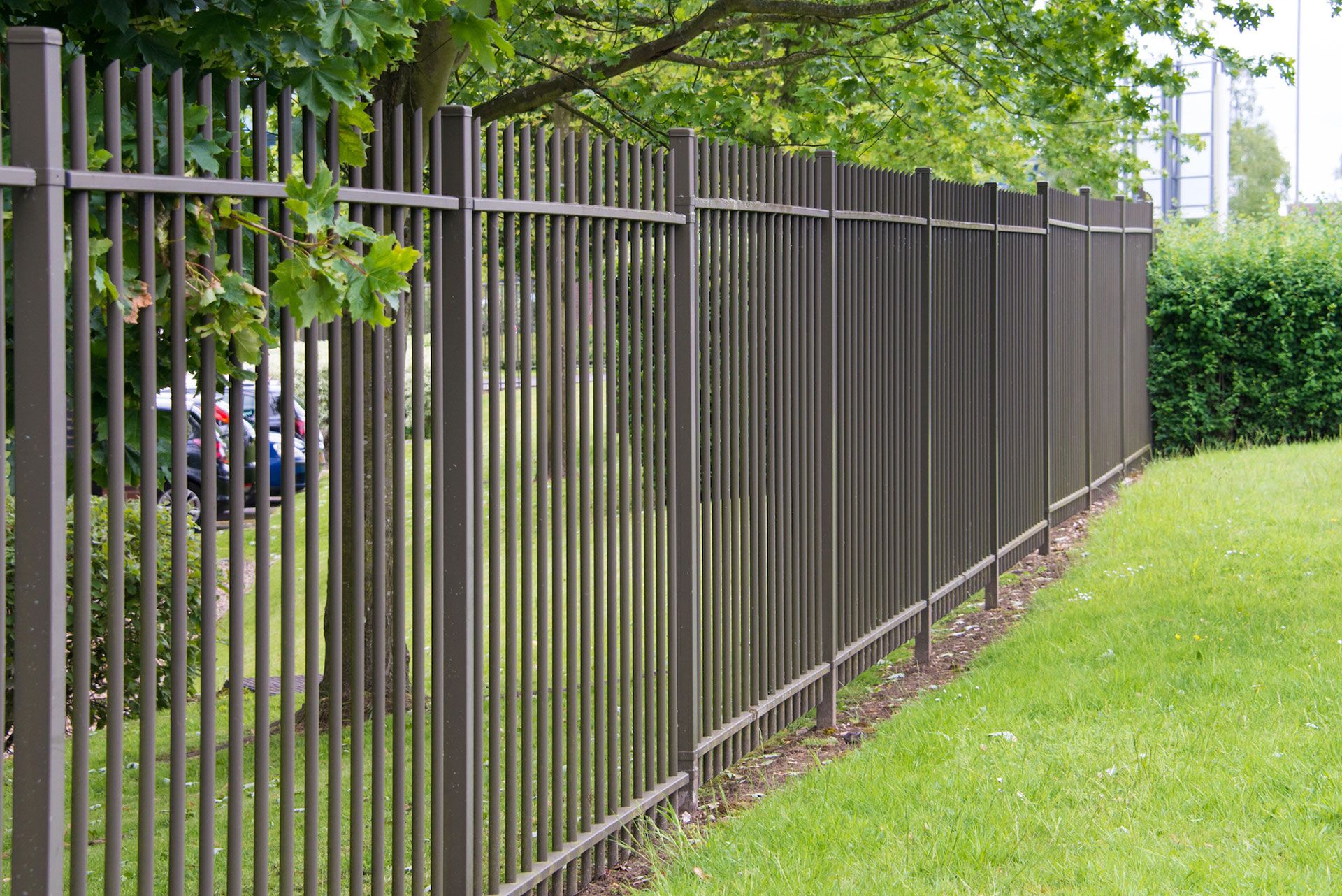 A metal fence surrounds a lush green field.
