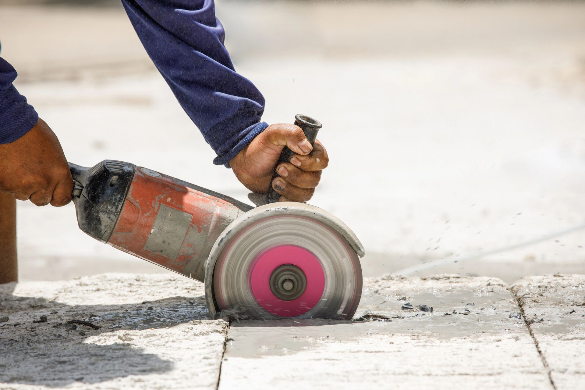 A man is using a grinder to cut a hole in a concrete floor.
