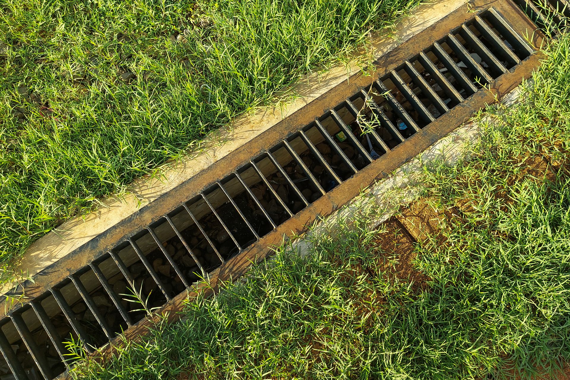 An aerial view of a drain in the middle of a grassy field.
