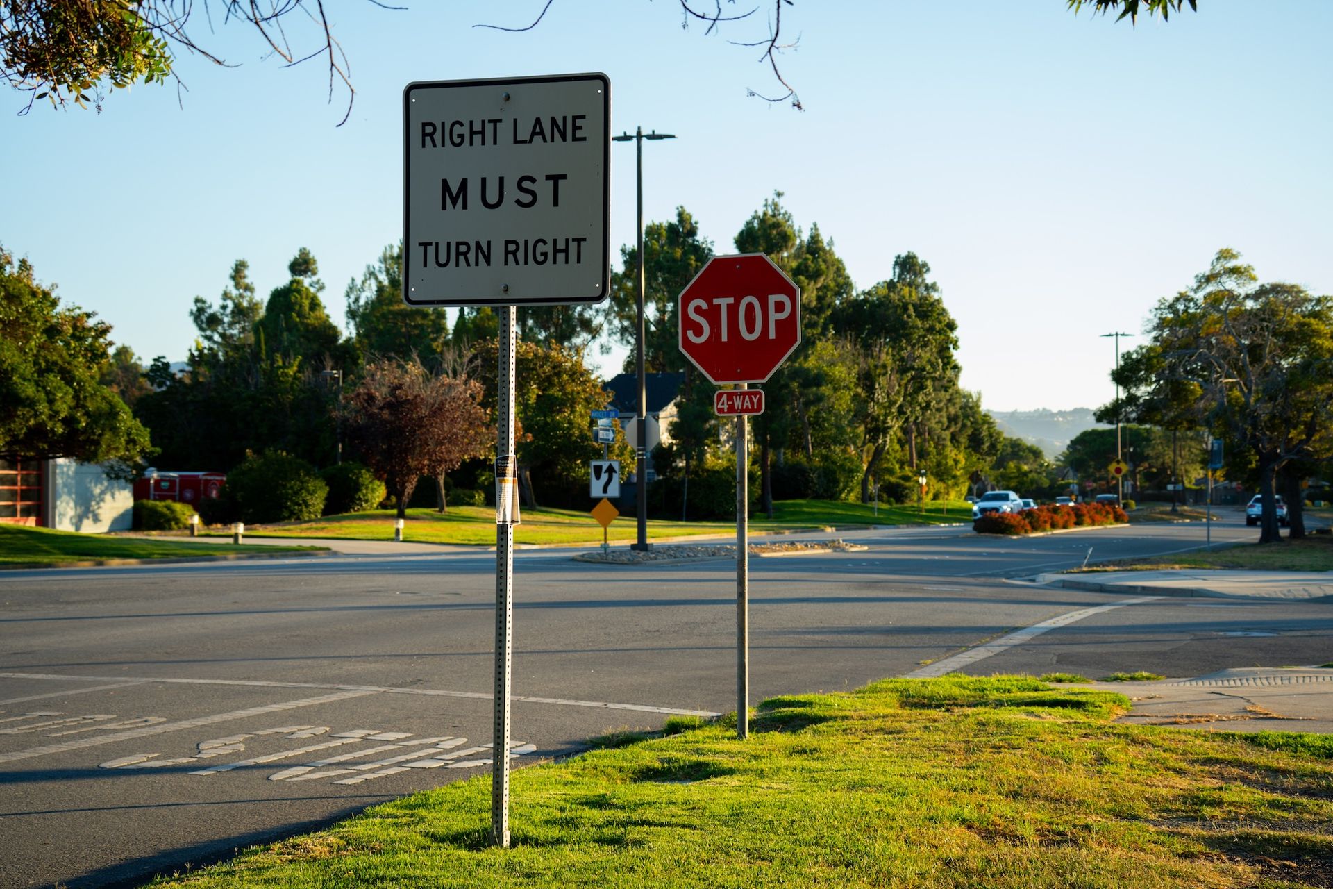 Road intersection with a right-turn-only sign and a stop sign beside a grassy median.