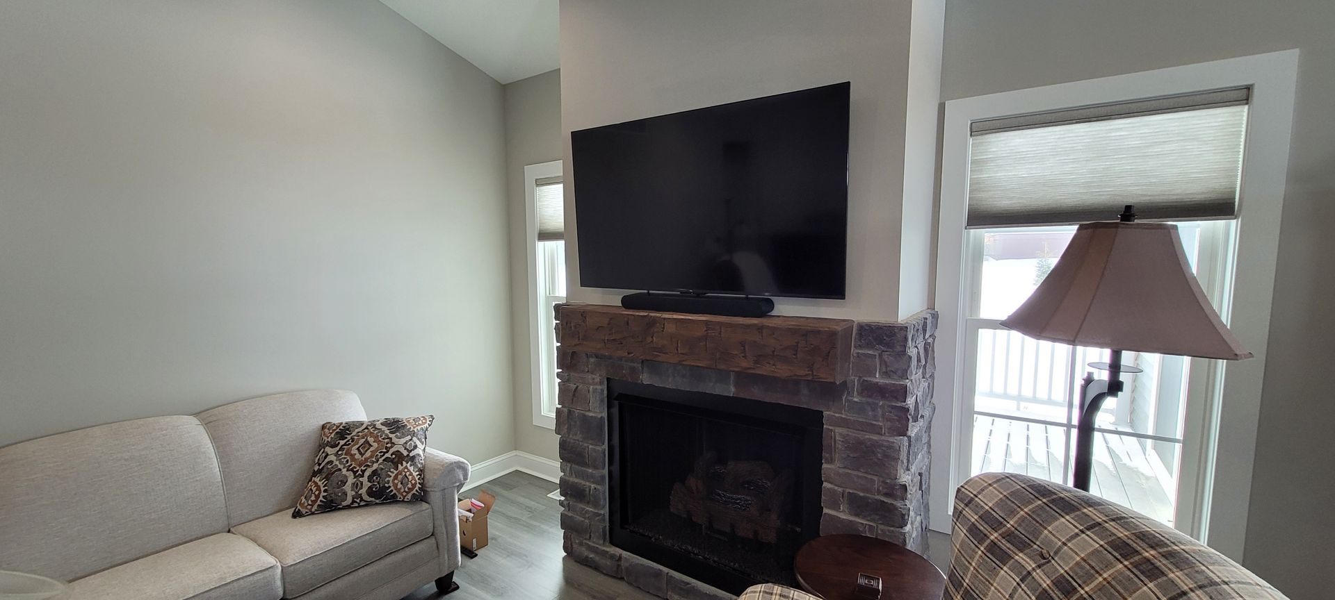 Living room with sofa, fireplace with mounted TV, and window with blinds.