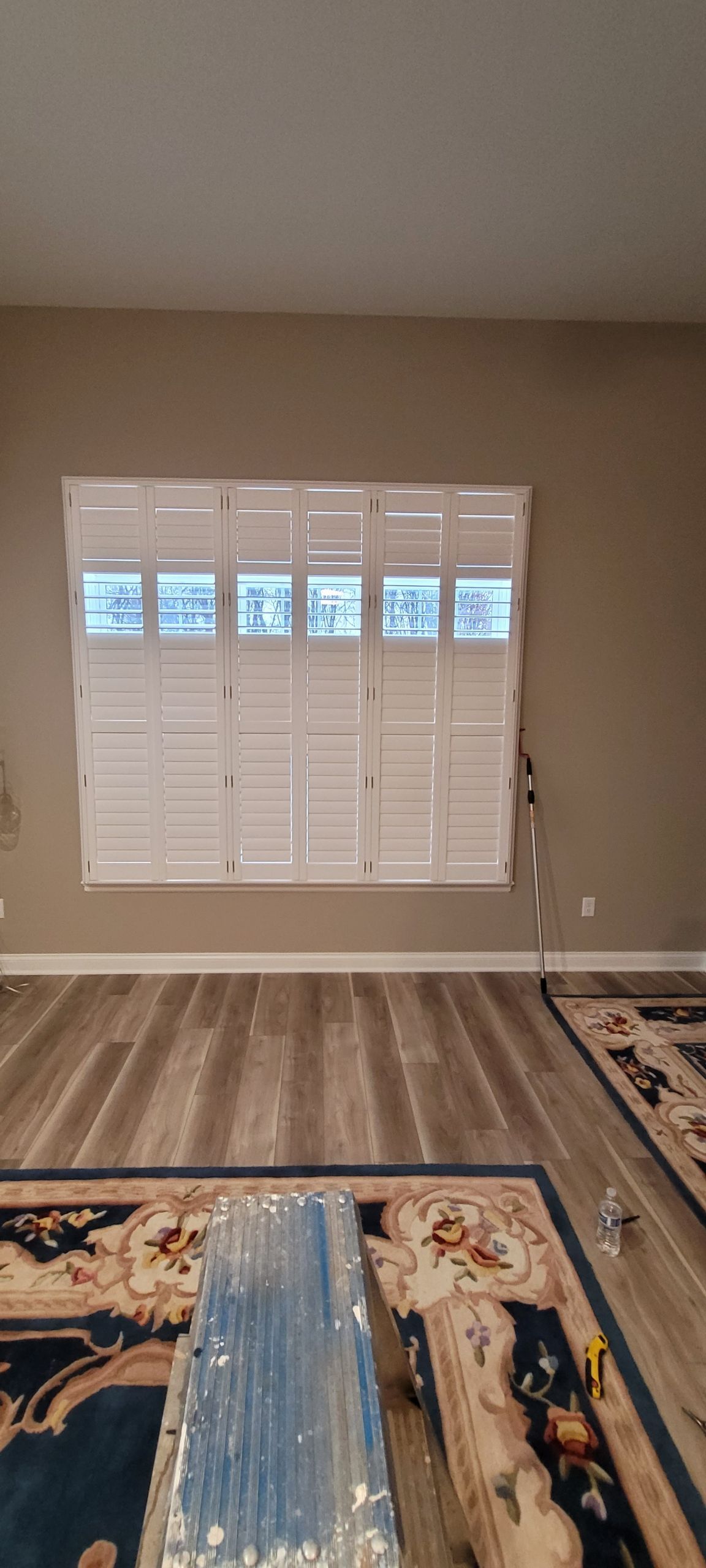 Interior view with a large window covered by white shutters,