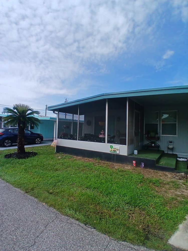 A mobile home with a screened in porch and a palm tree in front of it
