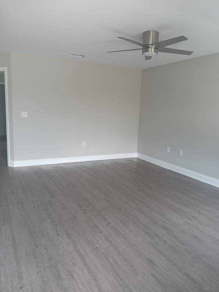 An empty living room with hardwood floors and a ceiling fan