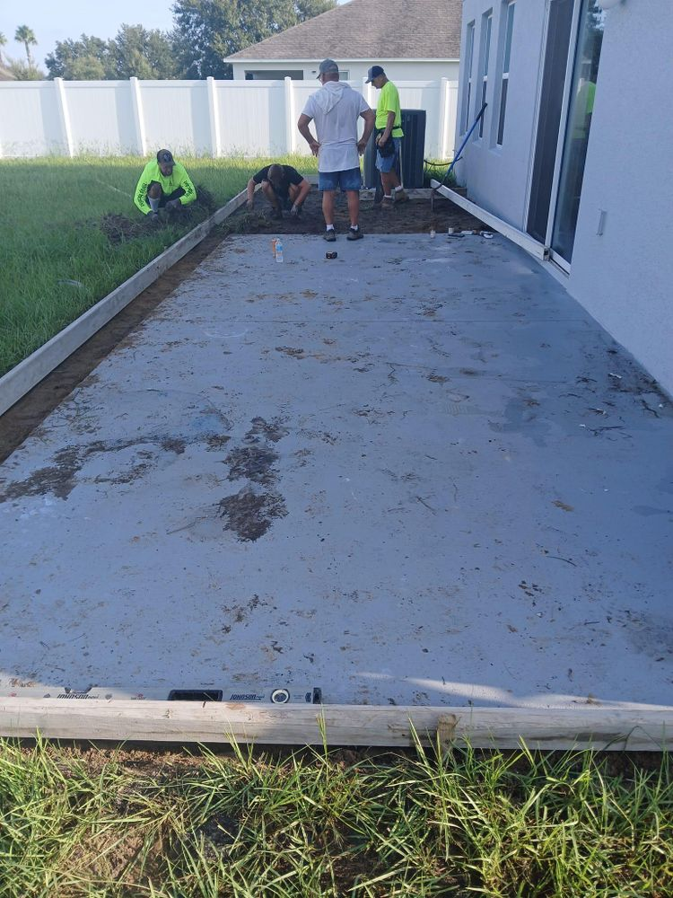 A group of men are working on a concrete patio in a backyard.