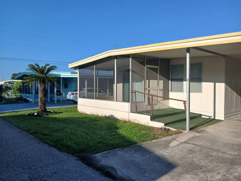 A mobile home with a screened in porch and stairs